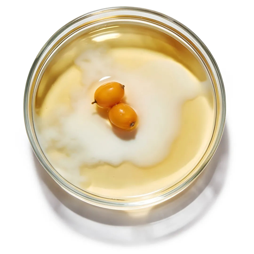 Sea buckthorn berries in a slightly emulsified liquid inside a glass petri dish on a white background, representing Yelf Clean Affairs Oil-to-Milk Cleanser