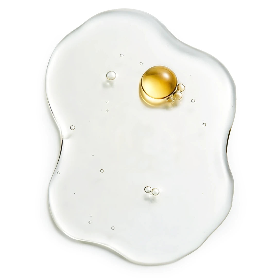 Clear hydrating liquid with multiple small droplets and a soft golden oil cluster on a white background, representing vitamin E and sodium PCA in Yelf Spot Off Pigment Fix Serum.