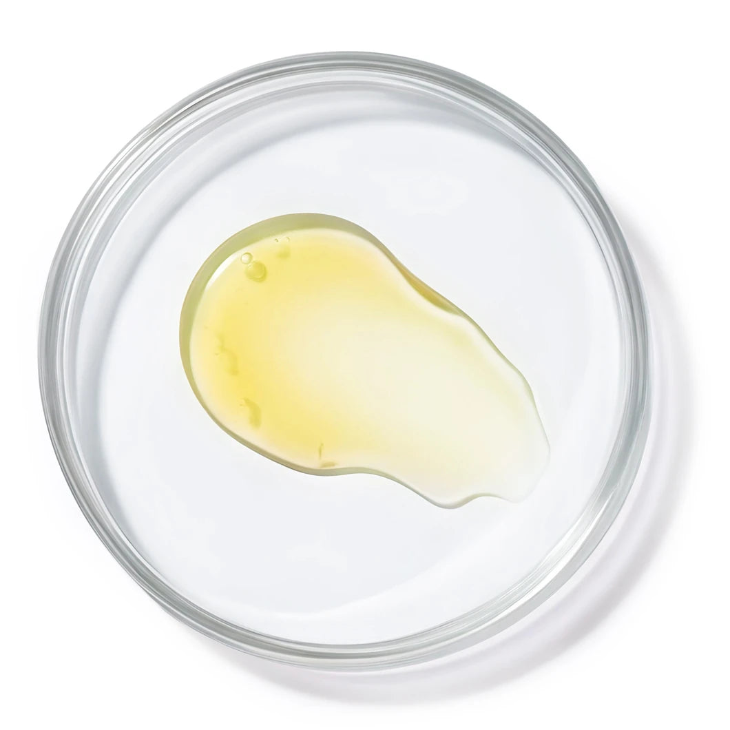 Transparent liquid with a subtle yellow tint in a petri dish on a bright white background, representing Yelf Aging Bye Bye Vitamin-C Serum