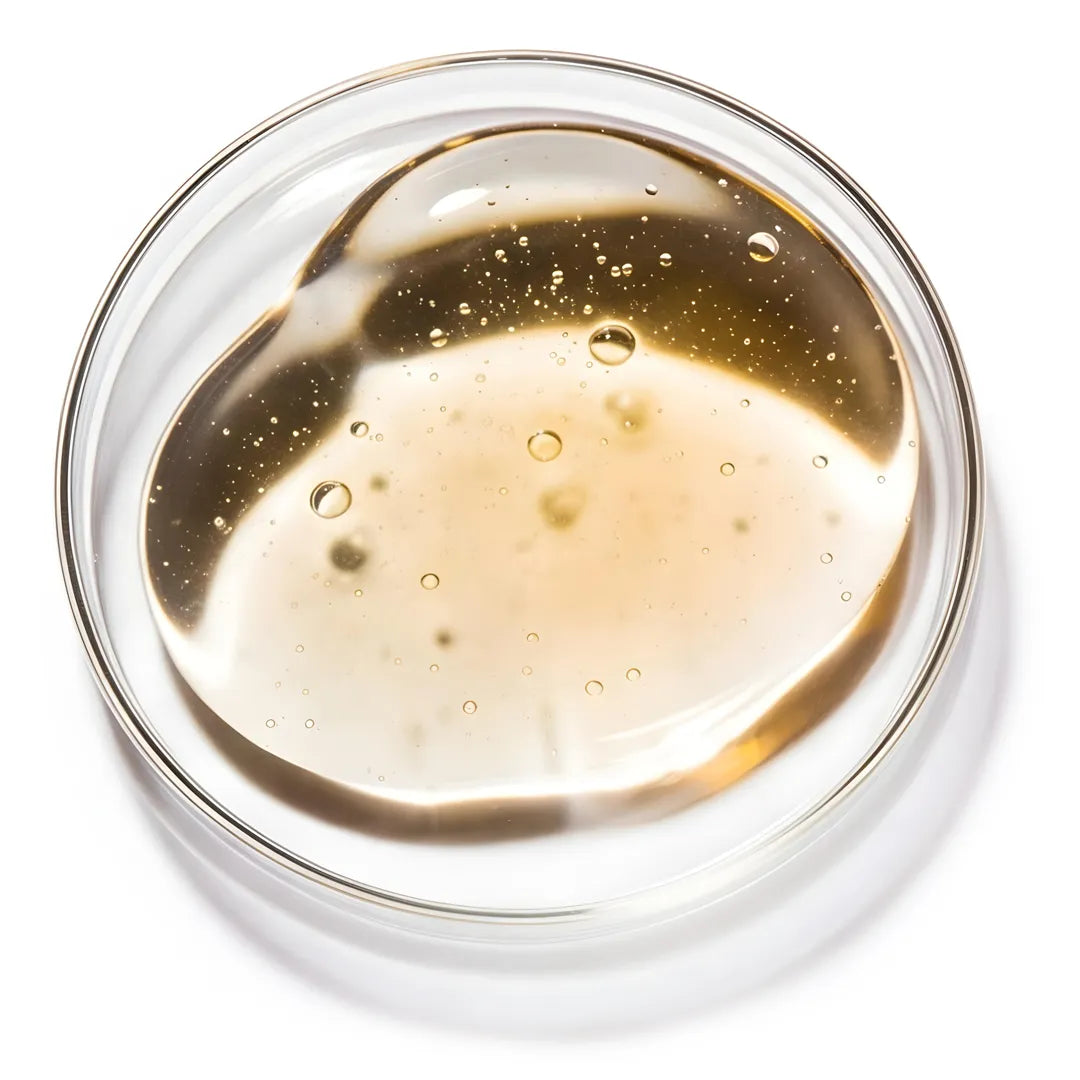 Top view of a transparent hyaluronic acid gel texture with air bubbles in a glass dish, showcasing hydration and lightweight skincare consistency