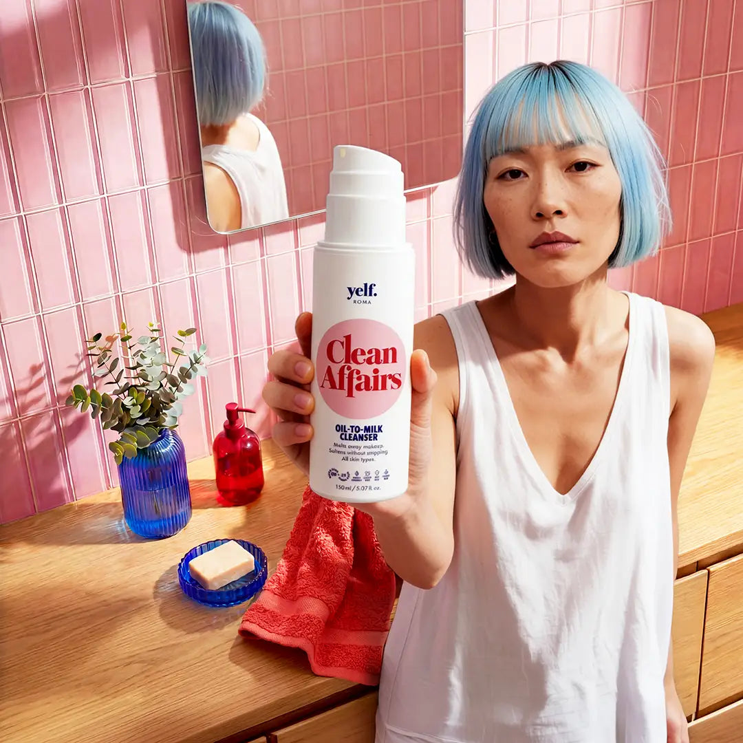 Model holding Yelf Clean Affairs Oil-to-Milk Cleanser in a colorful pink bathroom with warm sunlight, glossy tiles and modern skincare lifestyle aesthetic.