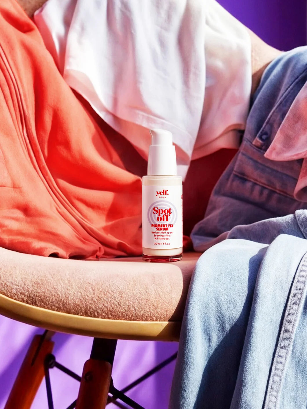 Yelf Spot Off Pigment Fix Serum on a chair surrounded by casually placed clothing in a colorful everyday lifestyle scene