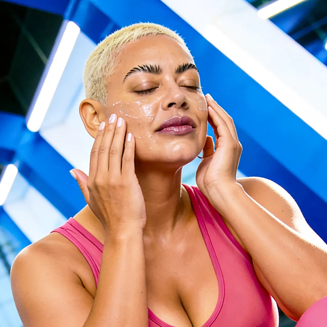 Model applying Yelf Viva el Boost Caffeine Gel after workout in a vibrant gym environment with glossy skin, colorful activewear and energetic fitness mood.