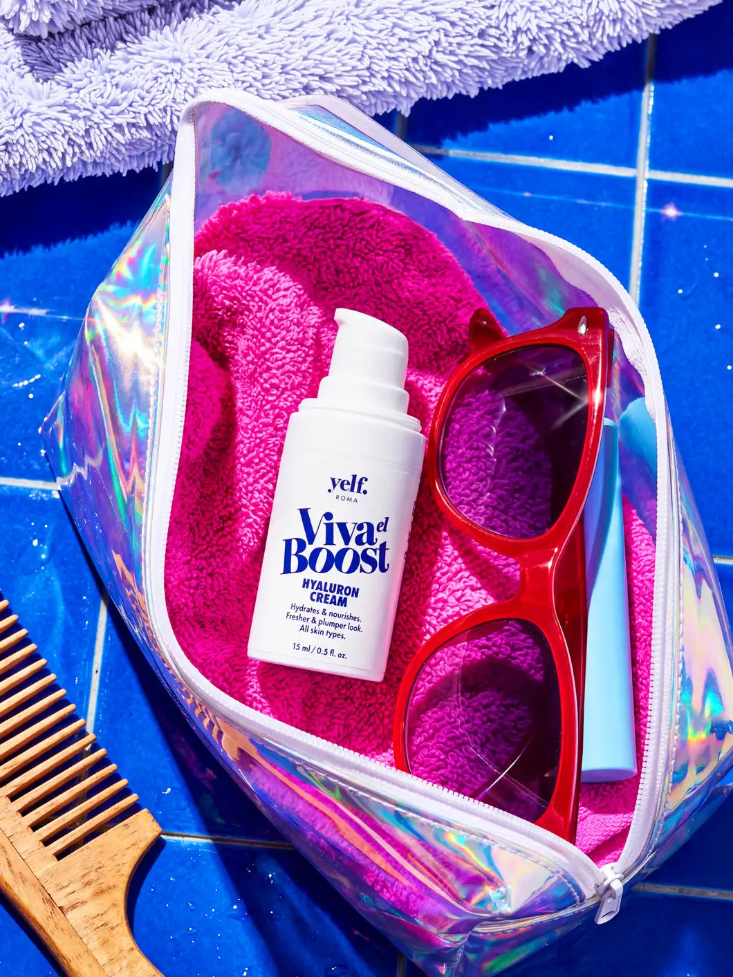 Yelf Viva el Boost Hyaluron Cream inside an iridescent transparent cosmetic pouch with pink towel, red sunglasses and blue accessories on glossy blue pool tiles in bright summer sunlight.